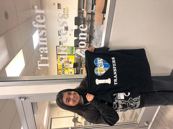 Woman holding shirt that says " I heart UCR transfers" in front of study room